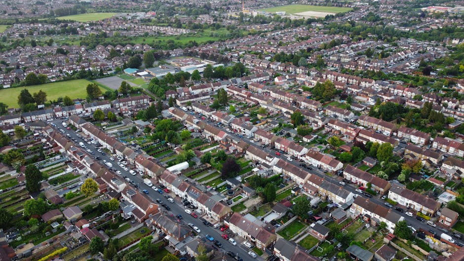 Aerial view of a residential neighborhood in Merton, showing rows of terraced houses with tiled roofs, front gardens, and parked cars along the streets. The image captures the layout of the SW19 and C