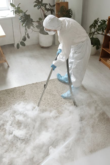A person using a vacuum cleaner to deep clean an oriental-style area rug with intricate floral patterns in a residential living room. The individual, dressed casually in jeans and sneakers, holds the